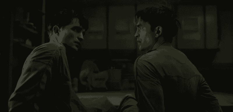 “Still from Mickey 17 (2025), featuring two versions of the same man facing each other in a dimly lit room.”