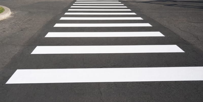 Freshly painted white crosswalk bars on asphalt