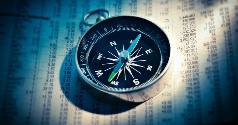 A compass resting on a page filled with financial numbers, symbolizing navigating data or markets.