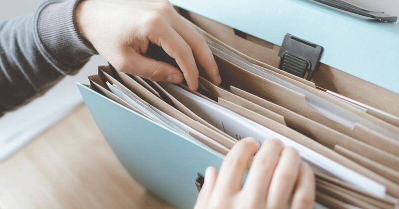書類整理をする手元の写真、終活のためのファイルと書類.