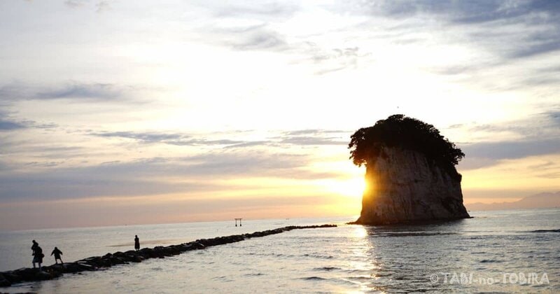 子供たちが石の道を朝日に照らされて見附島に向かって歩く様子