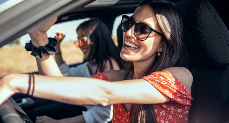 Young driver and passengers smiling and enjoying a car rental student discount