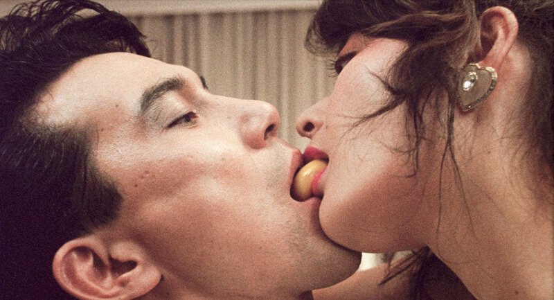 Close-up of two people sharing an egg yolk in a sensual scene from the film “Tampopo” (1985).