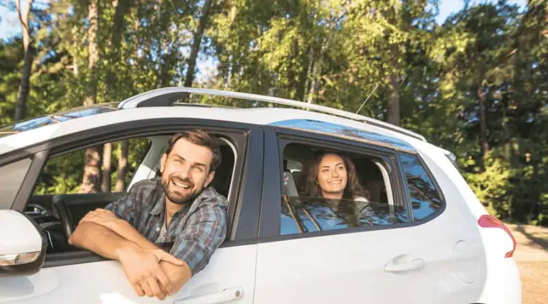 Foto de casal sorridente no carro para ilustrar artigo sobre pedágio free flow: como pagar