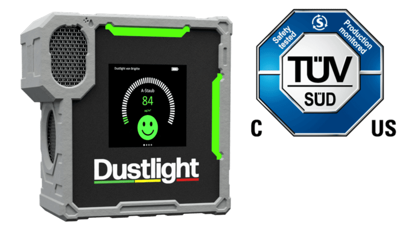 Dustlight Feinstaubmessgerät mit grünem Display und TÜV SÜD-Zertifizierungssiegel – tragbares Gerät zur Echtzeitüberwachung von A-Staub mit Smiley-Anzeige.