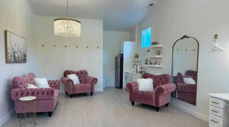 Bridal suite lounge at Romaine Valley with pink tufted velvet sofas, crystal chandelier and gold arched mirror