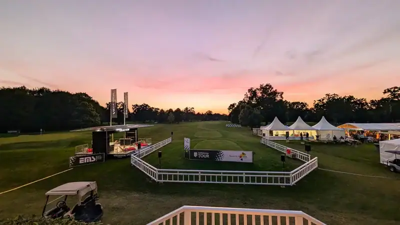 Veranstaltungsgelände auf einem Golfplatz bei Sonnenuntergang mit Zelten, Bühne und Werbebannern