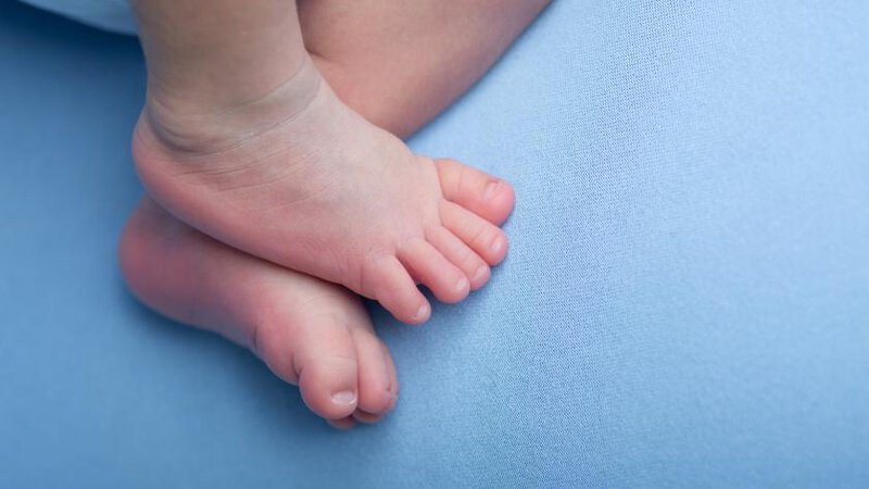 Pies de un bebé sobre una superficie de tela azul en Comunidad de Madrid.