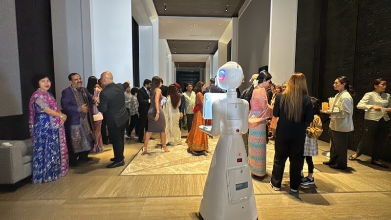 White robot photo booth moving through a busy wedding reception hall