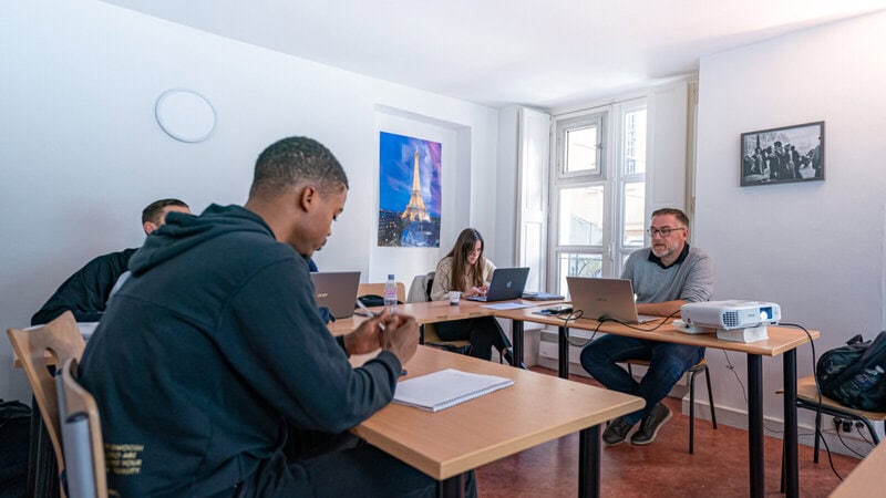 Moderner Unterricht in einer Sprachschule mit internationalen Teilnehmern und Laptops.