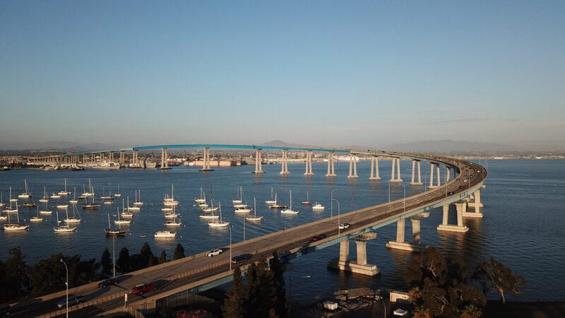 Die Coronado-Brücke in San Diego mit Segelbooten im Vordergrund und einer klaren blauen Himmel im Hintergrund.