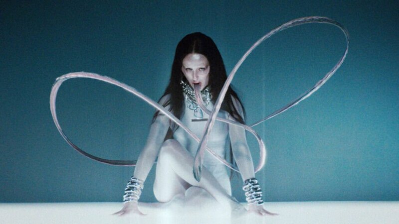 Bonnie Banane depicted with elongated, ribbon-like tongues in a futuristic blue setting from her video ‘Hoes of Na’.