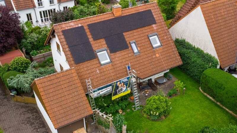 Abbildung eines Einfamilienhauses mit PV-Anlage auf dem Dach, im Grünen mit Garten.