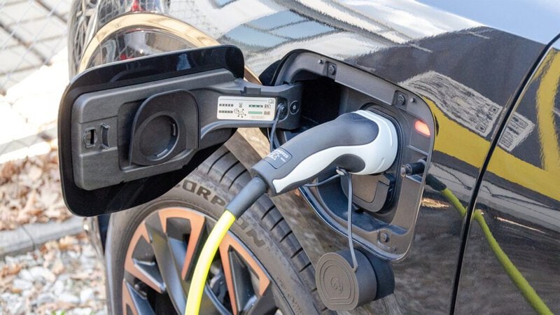 Darstellung eines offenen Tankdeckels eines Elektrofahrzeugs, das gerade mit Strom beladen wird.