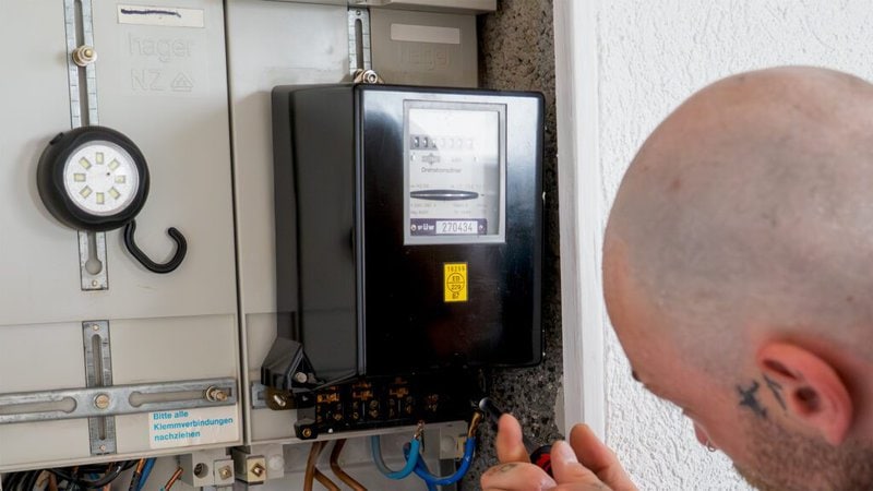 Darstellung eines Elektrikers an einem Stromzähler.