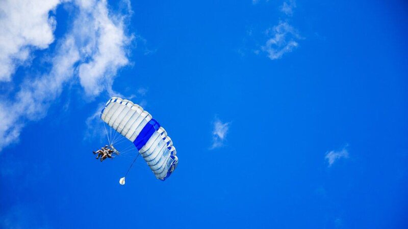 Quantilia logo with parachute against blue sky with clouds.