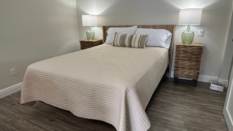 Cottage bedroom with queen bed and rattan nightstands at Romaine Valley Weddings & Events in Fenton, Missouri