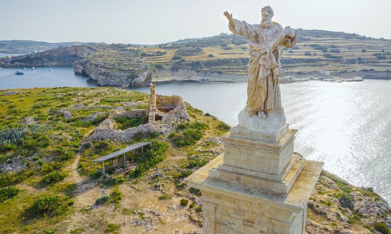 Historische Statue mit Blick auf eine malerische Küstenlandschaft auf Malta.