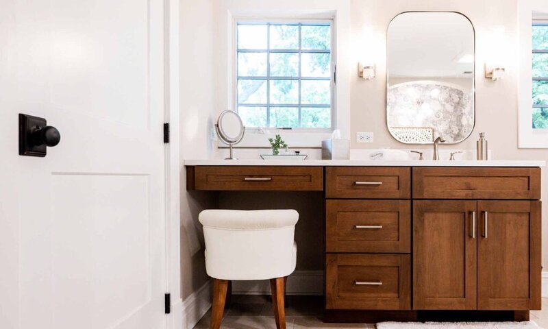 primary bathroom with wood cabinets, windows and makeup station