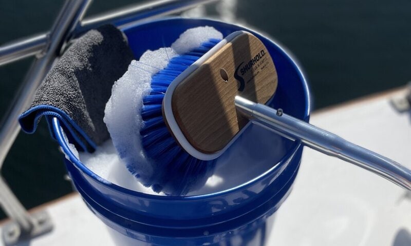 Emmer gevuld met schoonmaakmiddel en een borstel, gebruikt voor het schoonmaken van een boot