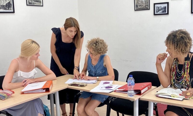 Französischkurs mit engagierter Lehrerin und Sprachschülerinnen in einer interaktiven Lernumgebung.