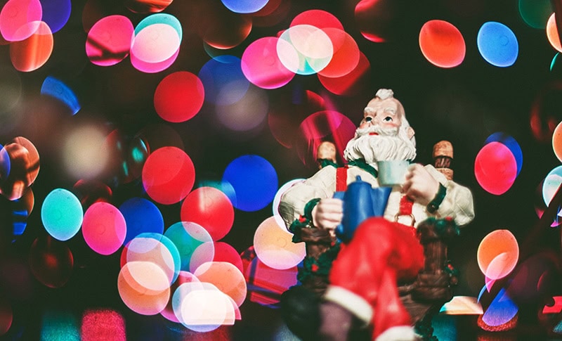 Santa figurine in front of blurry Christmas lights