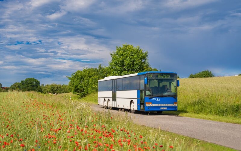 Bequemer Ausflugsbus der Ambos GmbH auf einer Landstraße.