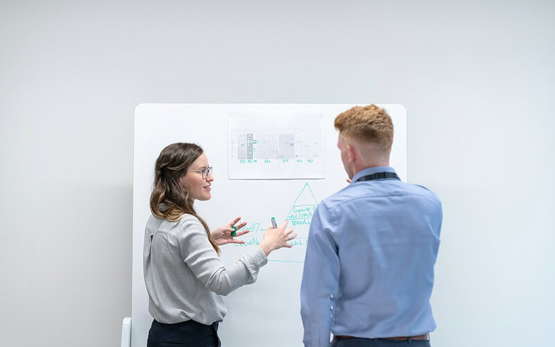 project near-misses — two colleagues discussing ideas at whiteboard