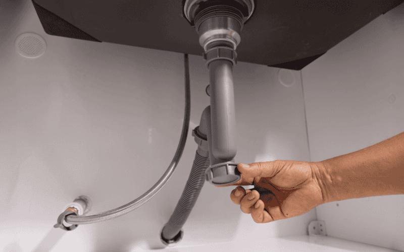 Plumber repairing or inspecting under sink plumbing system.