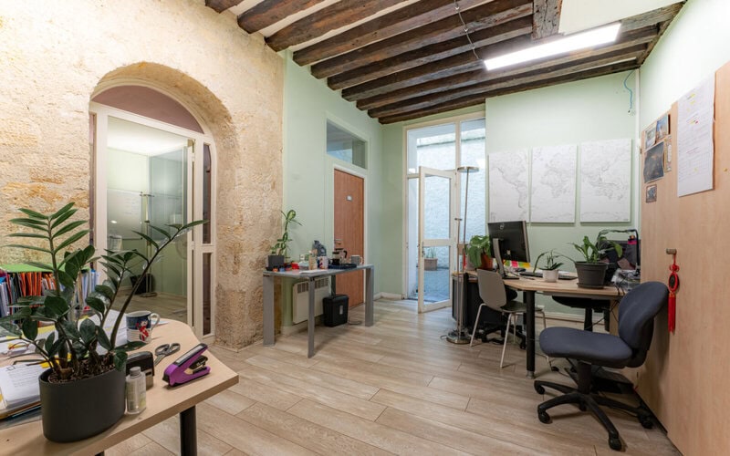 Modernes Büro mit rustikalen Steinwänden, Holzbalkendecke und Pflanzen.