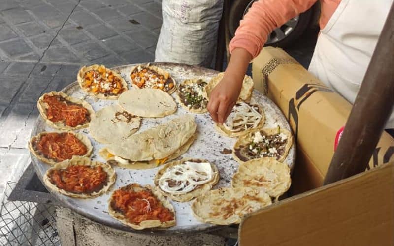 woman cooking Oaxaca memelas from a street food cart