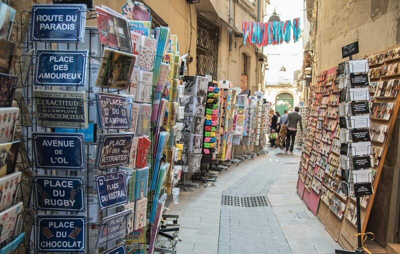 Französische Altstadtgasse mit Ständen voller Postkarten, Bücher und Souvenirs.