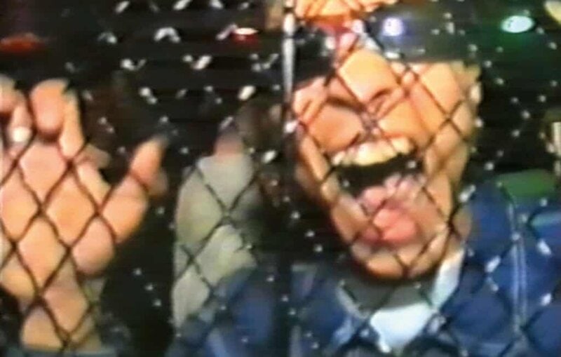 Excited clubgoer screaming behind metal barrier at 90s underground rave