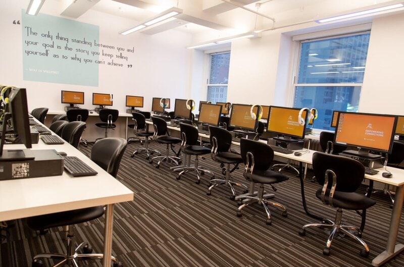 Ein modernes Computerlabor mit mehreren Arbeitsplätzen, Monitoren und Headsets in einer Bildungseinrichtung.