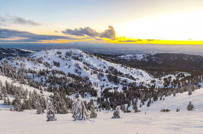 View of the Boise Valley from the top of Bogus Basin Mountain Recreation area during sunset with clouds on the horizon