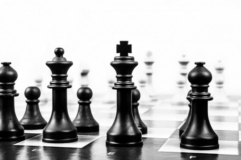 Chess pieces on a board, focusing on the king and queen in black and white.
