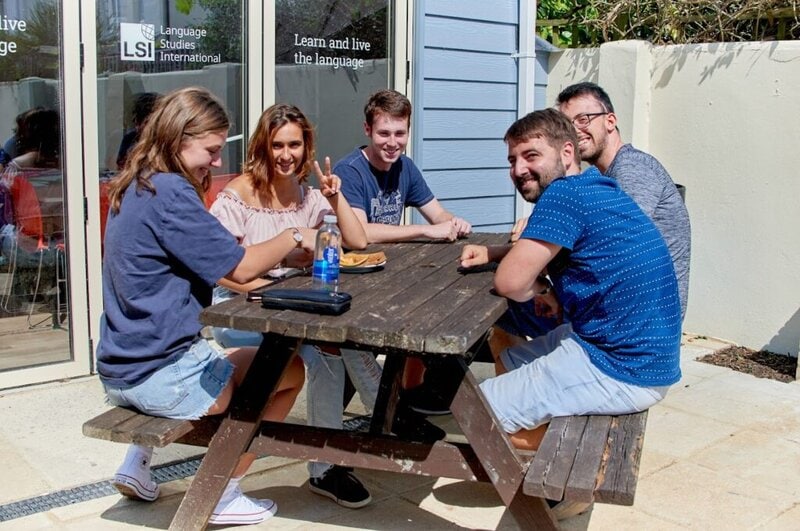 Gruppe internationaler Sprachschüler entspannt sich auf der Terrasse einer Sprachschule in Brighton.