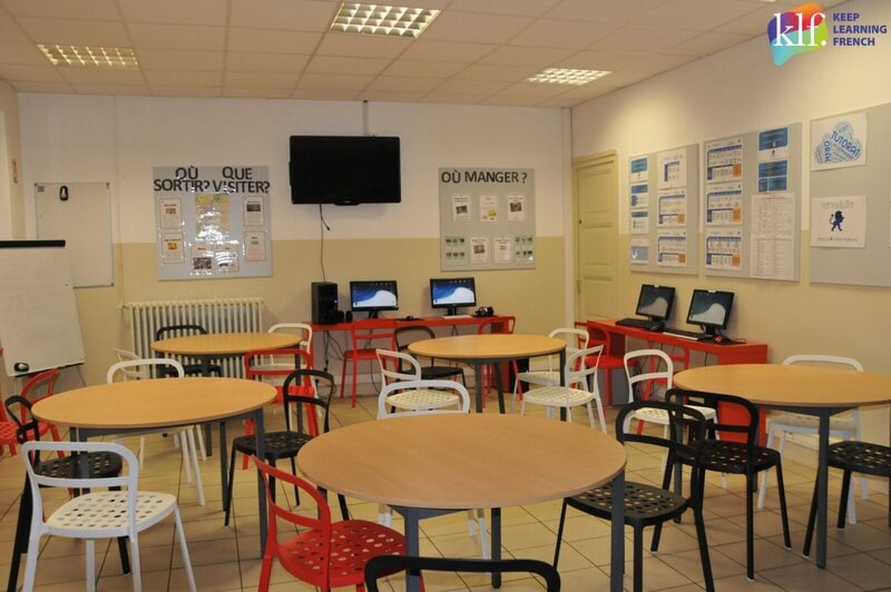 Gemeinschaftsraum der Sprachschule Lyon Bleu International mit Computerecke und Infotafeln.