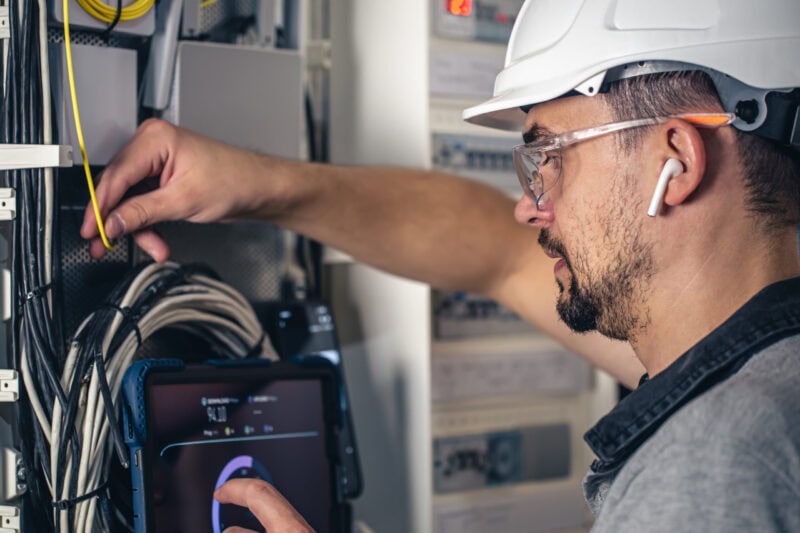 Man, an electrical technician working in a switchboard with fuses.