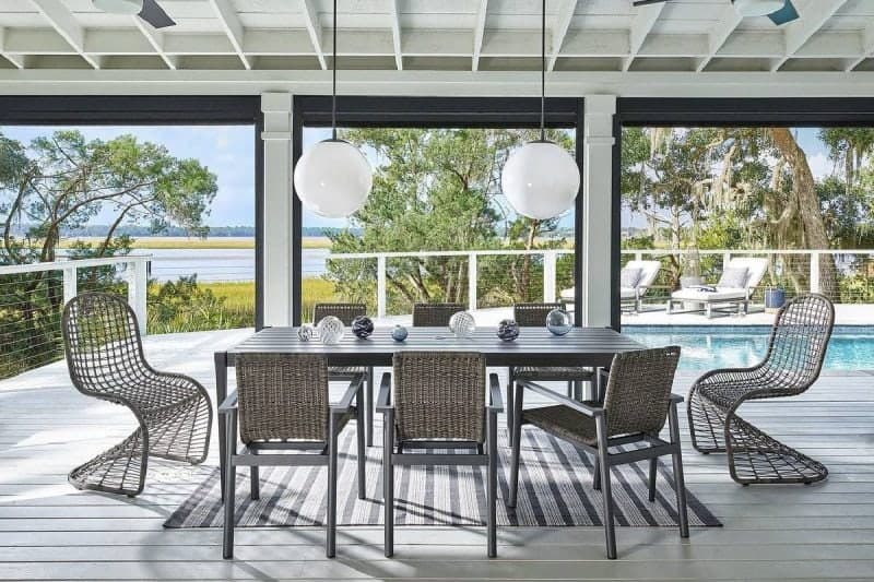 Bright modern indoor dining with waterfront view, outdoor pool, and lush greenery.