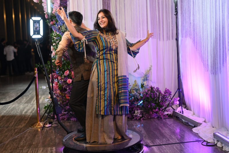 Wedding guest in a festive Indian outfit dancing on the 360 video booth platform
