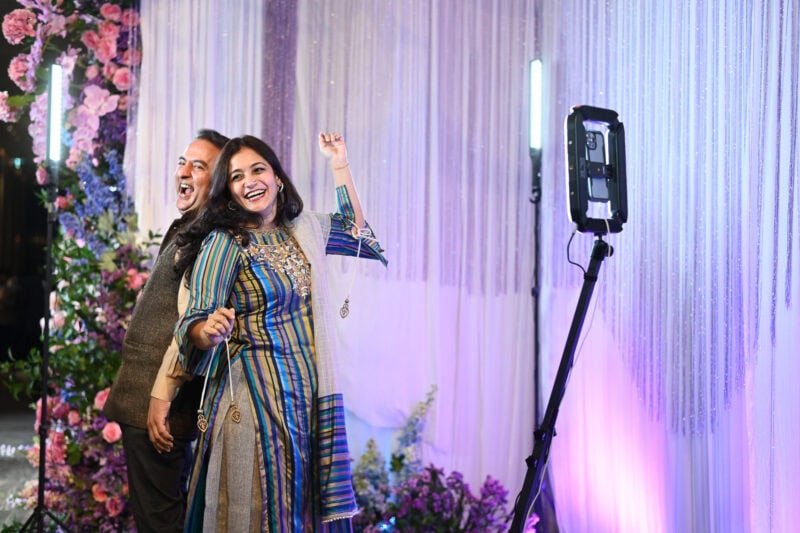 Wedding guests in Indian outfits laughing and posing at the 360 booth
