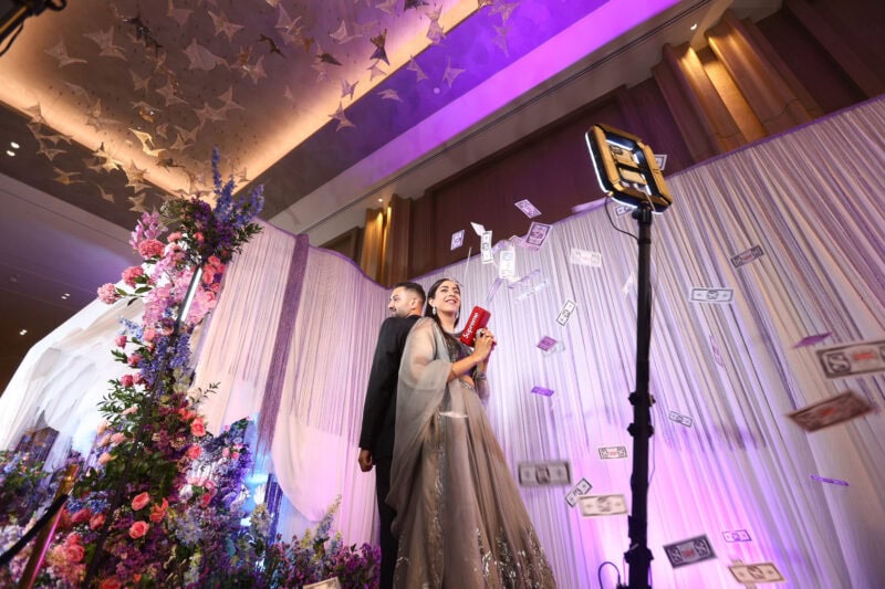 Bride and groom on the 360 video booth platform as guests throw flower petals at a wedding