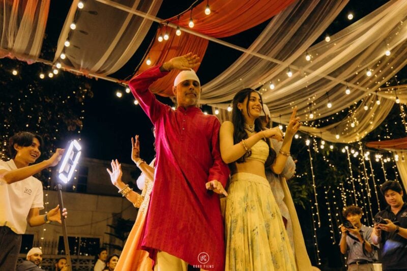 Guests in red and gold Indian wedding outfits dancing at the 360 video booth at night
