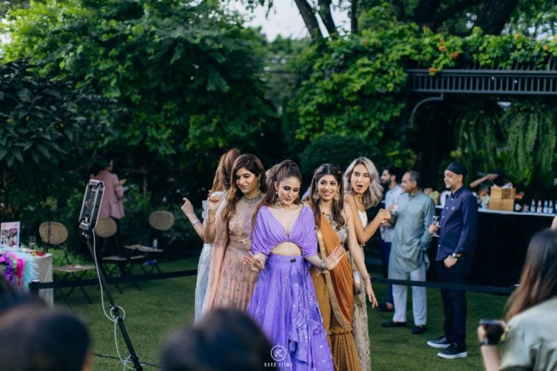 Bridesmaids in pastel gowns waiting their turn at the 360 booth at a garden wedding