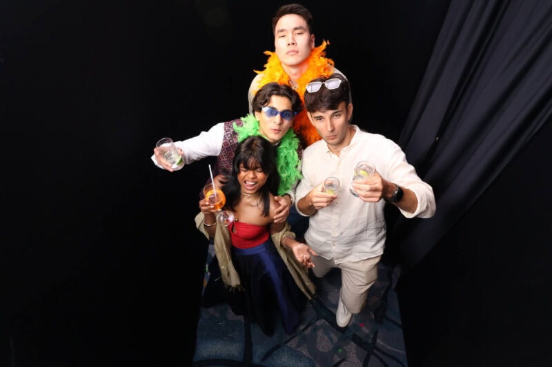 Four guests with sunglasses and feather boas photographed from above in a top view photo booth