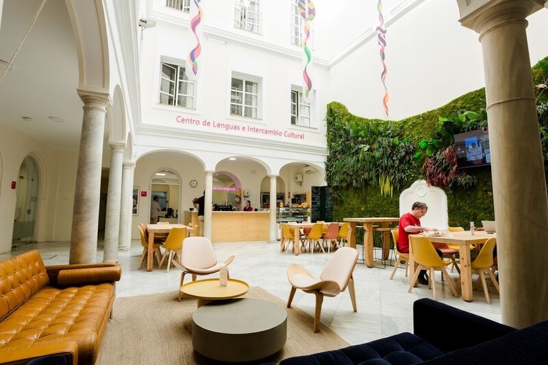 Modernes Sprachzentrum mit Cafébereich und vertikalem Garten in einem hellen, offenen Innenhof.