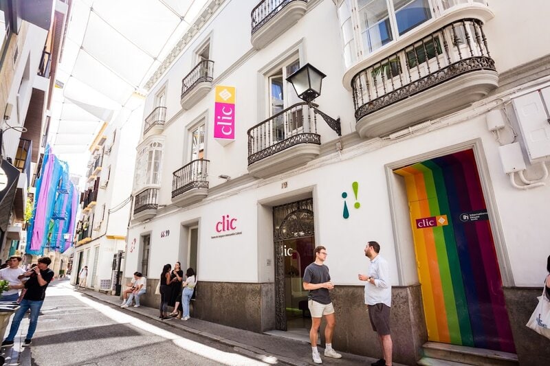 Vorderansicht der Sprachschule Clic in Sevilla mit Studierenden vor dem Eingang in einer sonnigen Gasse.