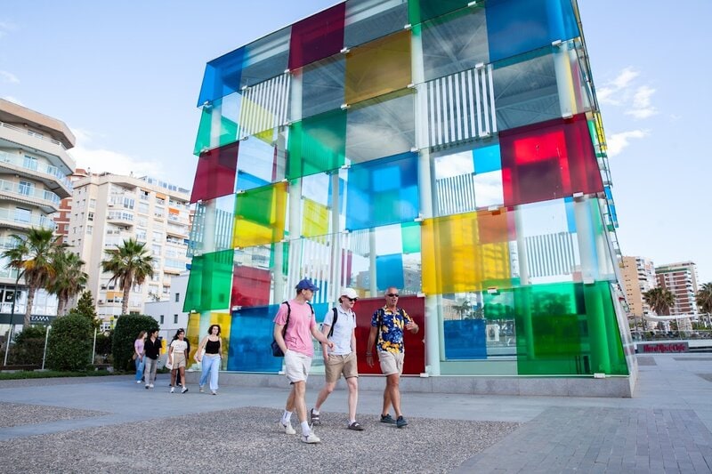 Das bunte Glaskubus-Gebäude Centre Pompidou Málaga mit Spaziergängern im Vordergrund