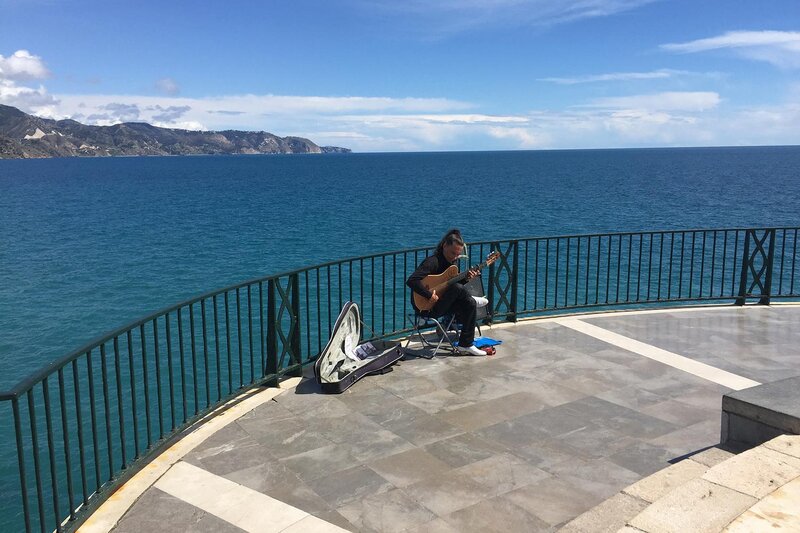 Straßenmusiker spielt Gitarre am Balcón de Europa in Nerja mit Blick auf das blaue Mittelmeer